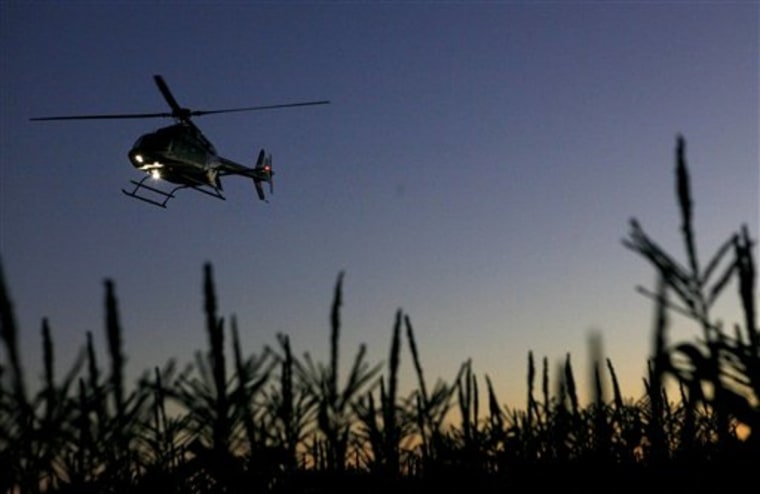 A helicopter flies over a field of corn before dawn to push warmer air closer to the plants Dec. 8 in an attempt to protect the corn from frost damage in Belle Glade, Fla.